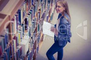 Standing student reading book in library