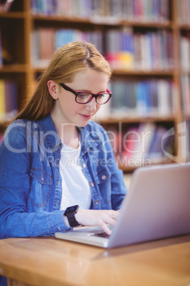 Student with smartwatch using laptop in library