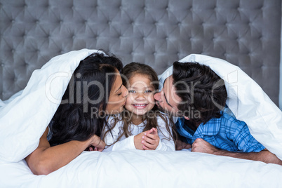 Happy parents kissing daughter