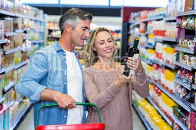 Smiling couple looking at bottle of wine