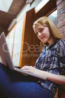 Focused student sitting on the floor against the wall using lapt