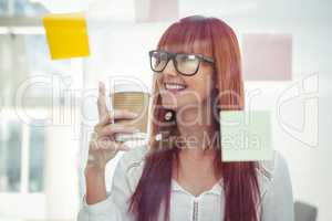 Attractive hipster woman with coffee cup looking at sticky notes