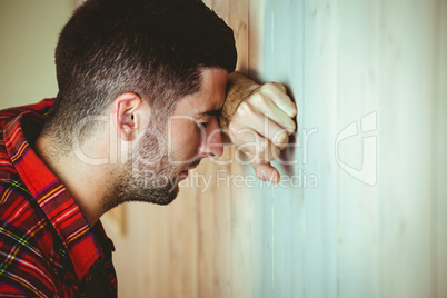Stressed man leaning against wall