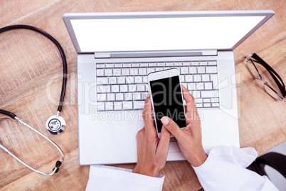 Doctor using smartphone on wooden desk