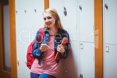 Pretty student with backpack leaning against the locker