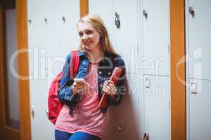 Pretty student with backpack leaning against the locker