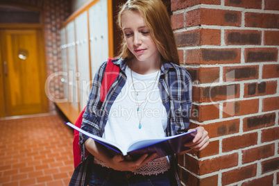 Focused student studying leaning against the wall