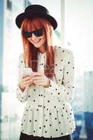 Smiling hipster woman texting with her smartphone