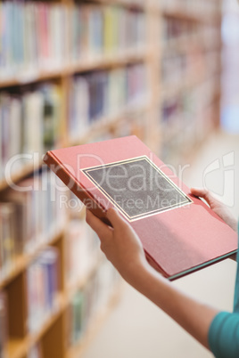 Over shoulder view of student in library holding book