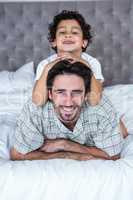 Smiling father and son on bed