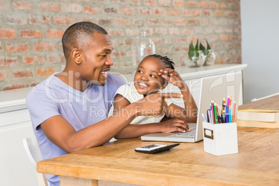 Cute daughter using laptop at desk with father