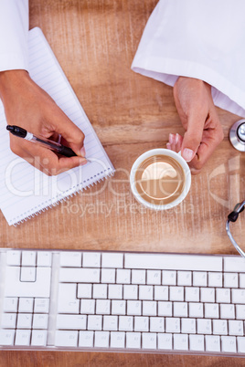 Doctor holding pen and hot beverage