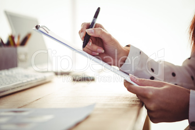 Cropped image of woman writing on clipboard