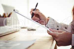 Cropped image of woman writing on clipboard