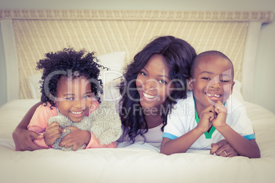 Mother and children lying on bed