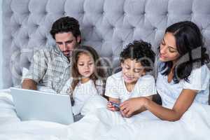 Happy family in bed shopping online