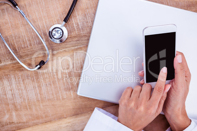 Doctor using smartphone on wooden desk