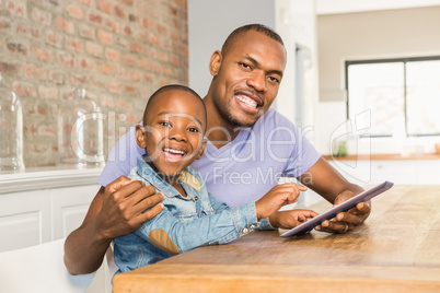 Cute son using tablet at desk with father Cute son using tablet at desk with father