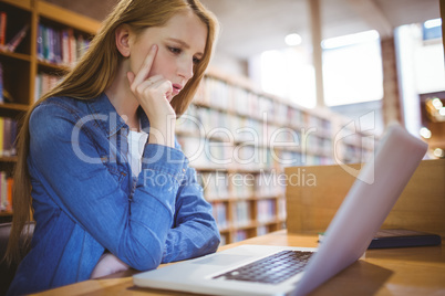 Focused student using laptop in library