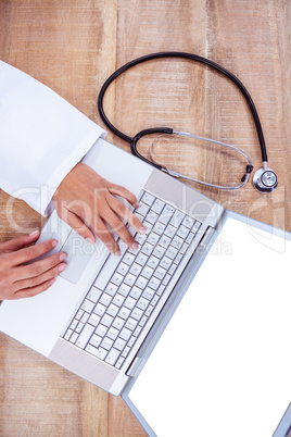 Doctor using laptop on wooden desk