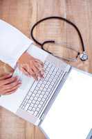 Doctor using laptop on wooden desk