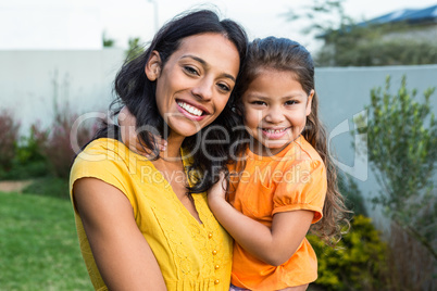 Standing mother holding her daughter outdoors