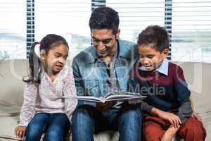 Happy father reading a book for his children