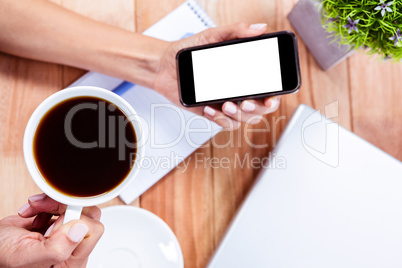 Overhead of feminine hands holding smartphone and black espresso