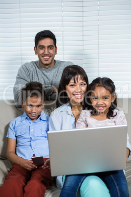 Smiling family using technology on the sofa