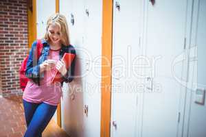 Pretty student with backpack leaning against the locker