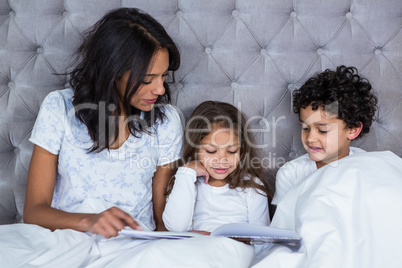 Happy family reading book on the bed