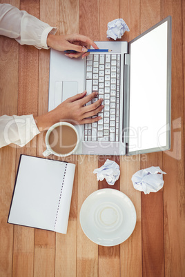 Cropped image of woman with pen using laptop
