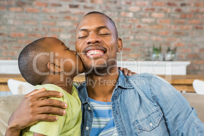 Son kissing his father on the couch