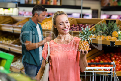 Smiling woman holding and looking a pineapple