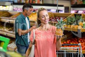 Smiling woman holding and looking a pineapple