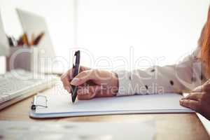 Cropped image of woman writing on notepad