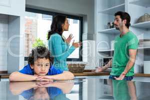 Sad child listening to parents argument