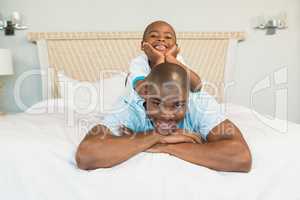 Smiling father and son lying on bed