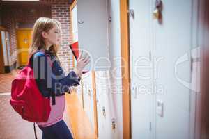 Pretty student with backpack putting notebook in the locker