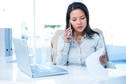 Smiling businesswoman on phone reading document