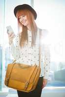 Smiling hipster woman texting with her smartphone