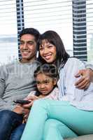 Smiling family watching tv on the sofa