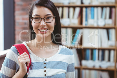 Smiling student with backpack standing in library