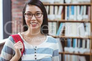 Smiling student with backpack standing in library