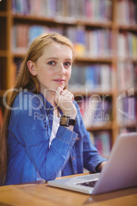 Student with smartwatch using laptop in library