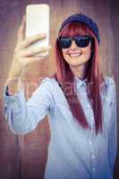 Smiling hipster woman taking selfie