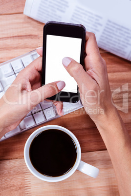 Businesswoman using her smartphone on desk