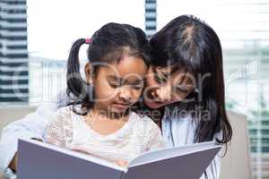 Happy mother reading book with her daughter