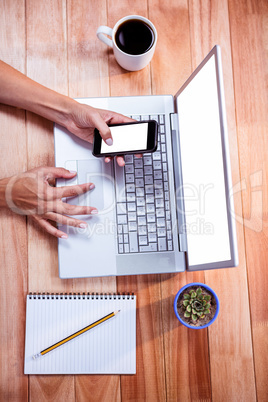 Overhead of feminine hands using laptop and smartphone