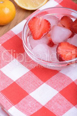 A slice of red strawberry on glass plate with lemon and mandarin in party theme background